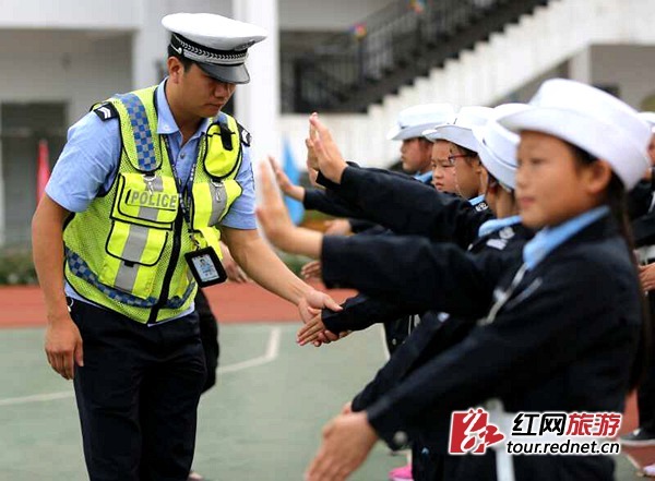 旅游"小交警"们在交警叔叔指导下练习交通指挥手势.