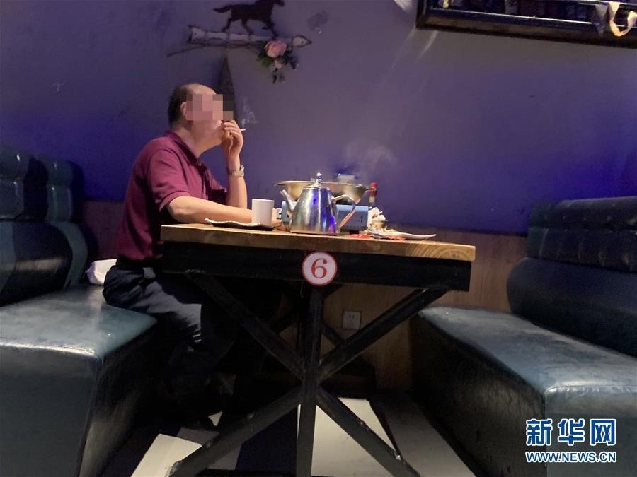 5月26日,北京经济开发区某烧烤店内,一位食客在室内吸烟(手机拍摄)。