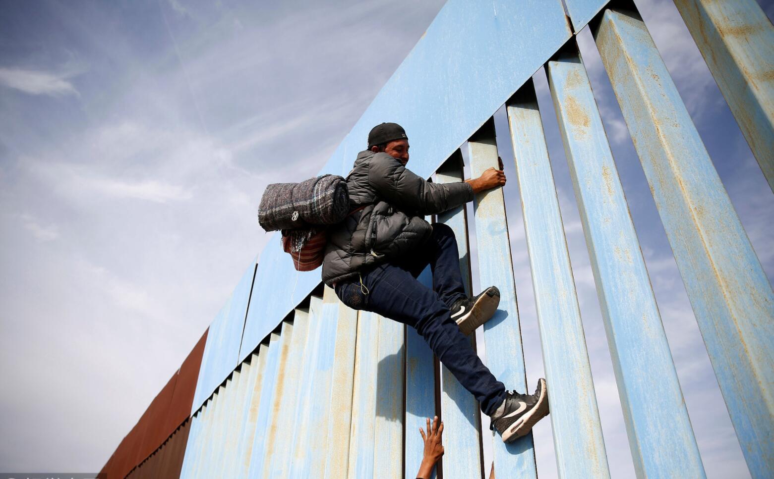 移民持续抵达美墨边境 徒手攀爬边境隔离墙