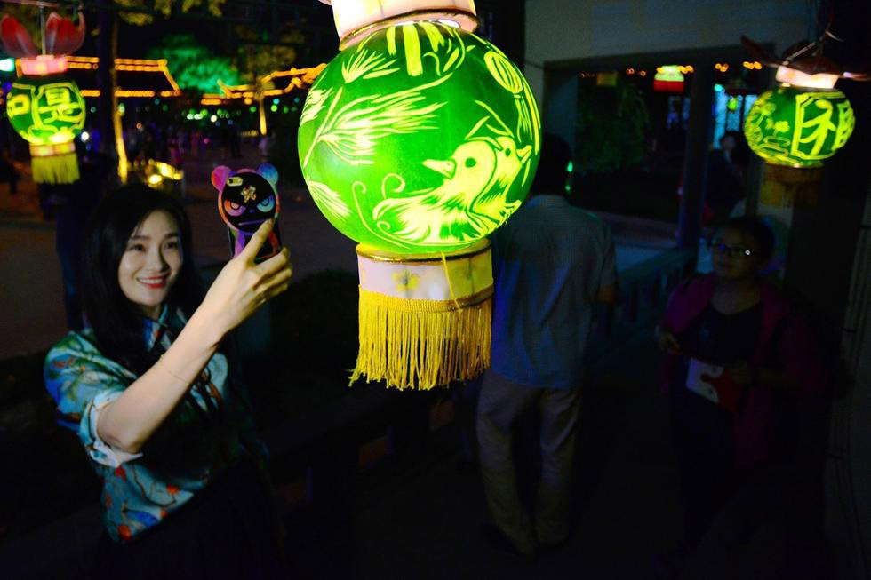 据悉，今年悬挂的仿瓜灯首次新增了印有报本塔、李叔同纪念馆等当地人文景观，让人耳目一新。图为：美女与“西瓜灯”合影。