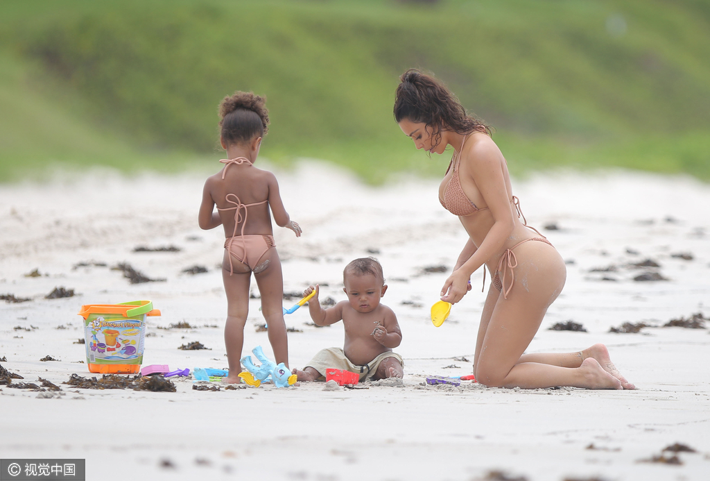 当地时间8月18日，金·卡戴珊（Kim Kardashian）带女儿小西北和儿子沙滩玩耍，卡戴珊身穿裸色系带比基尼，女儿与妈妈同款可爱十足，在沙滩上卡戴珊全程呵护幼子母爱爆棚，然而抢镜的还是翘臀。图为卡戴珊跪地与幼子玩耍。