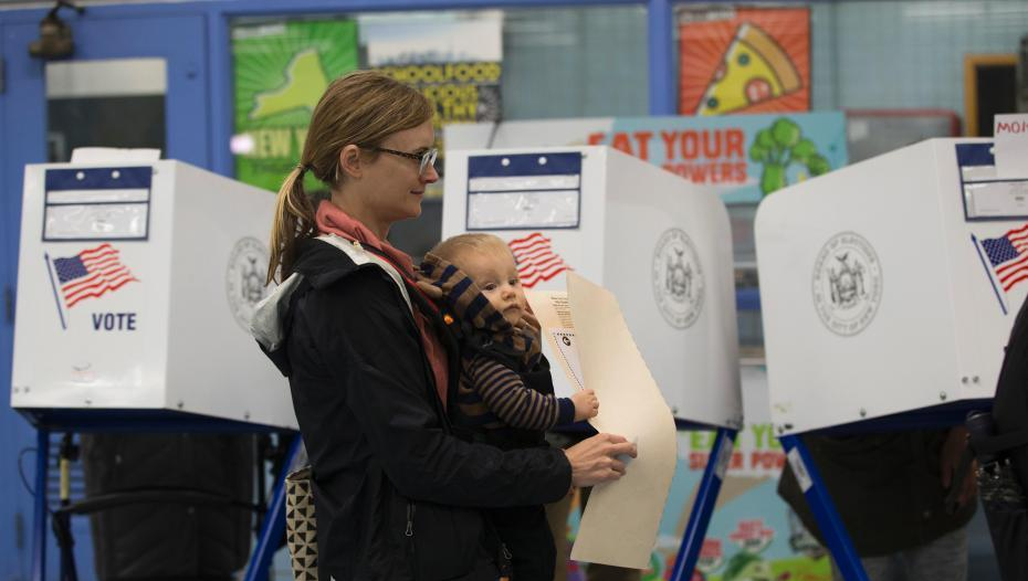 当地时间11月6日，美国2018年中期选举投票日，纽约一位母亲带着幼子在位于布朗克斯区的一处投票站投票。