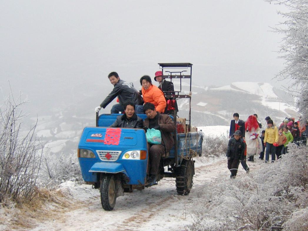 2007年铜川印台区官地村，农用三轮车拉着嫁妆，行走在泥泞的雪地里，一对新人步行走在后面。图片来源：姚忠智/视觉中国