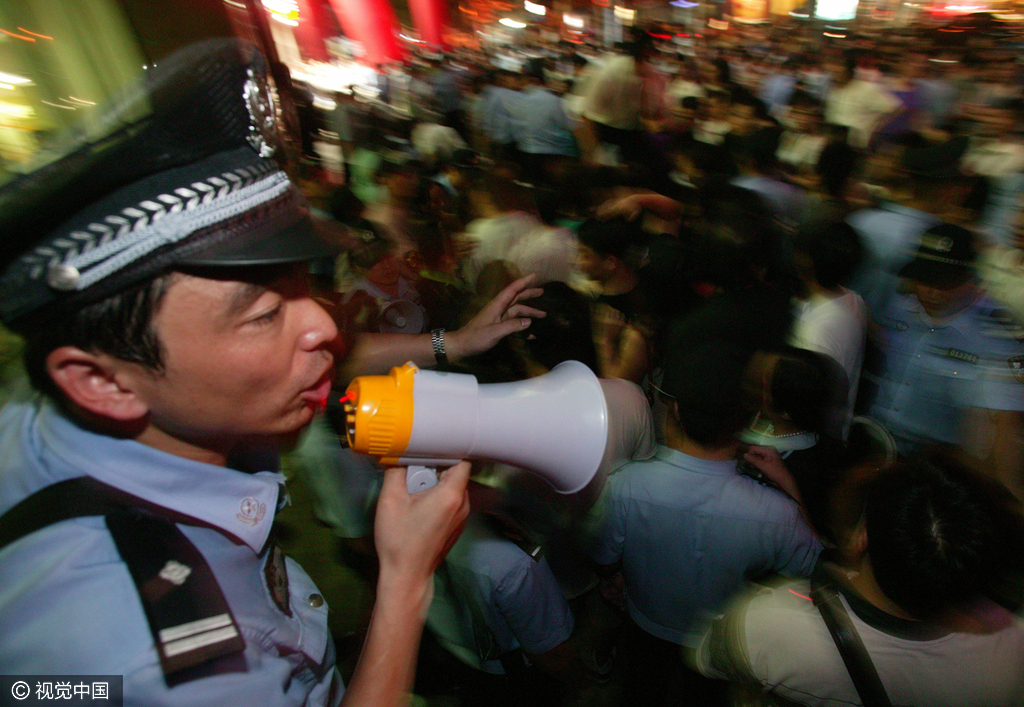 2009年7月25日夜，南京丹凤街上的卓越SOHO销售中心门外，成千人排队多日购买房子。警察现场维持秩序。