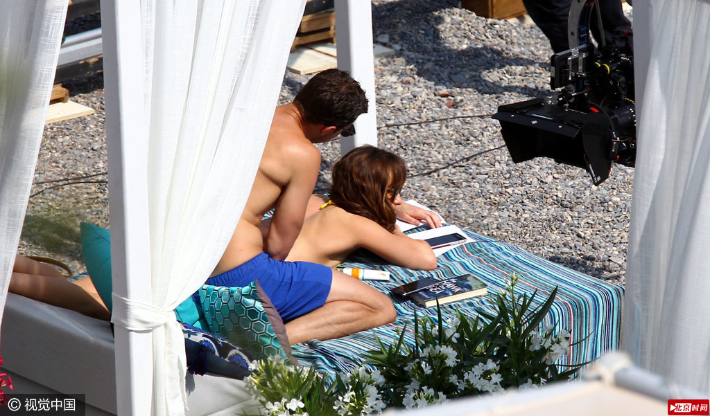 2016年7月12日，电影《五十度灰》拍摄现场。达科塔·约翰逊（Dakota Johnson）身着黄色比基尼脱Bra晒太阳，获詹米·多南（Jamie Dornan）解bra带。