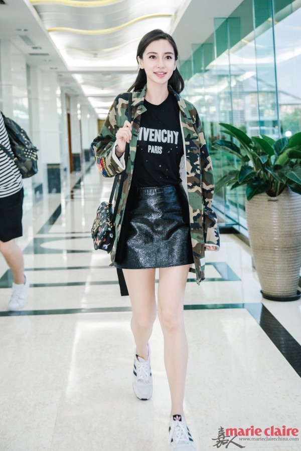 Angelababy现身机场。她身穿Givenchy黑色字母印花破洞圆领T恤，外搭迷彩外套，肩背Alexander McQueen黑色花朵印花手袋，下穿黑色亮片迷你裙，脚踩Adidas白色休闲鞋。