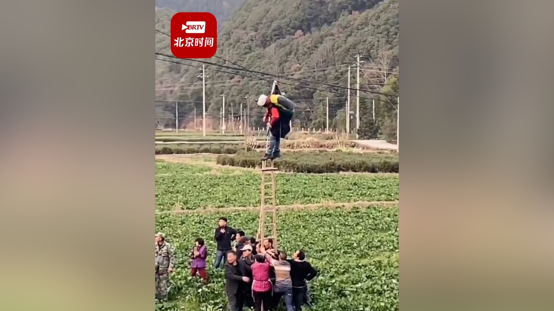 男子玩滑翔伞挂电线上村民搭梯救援：三四十人救了1个小时，所幸人平安！
