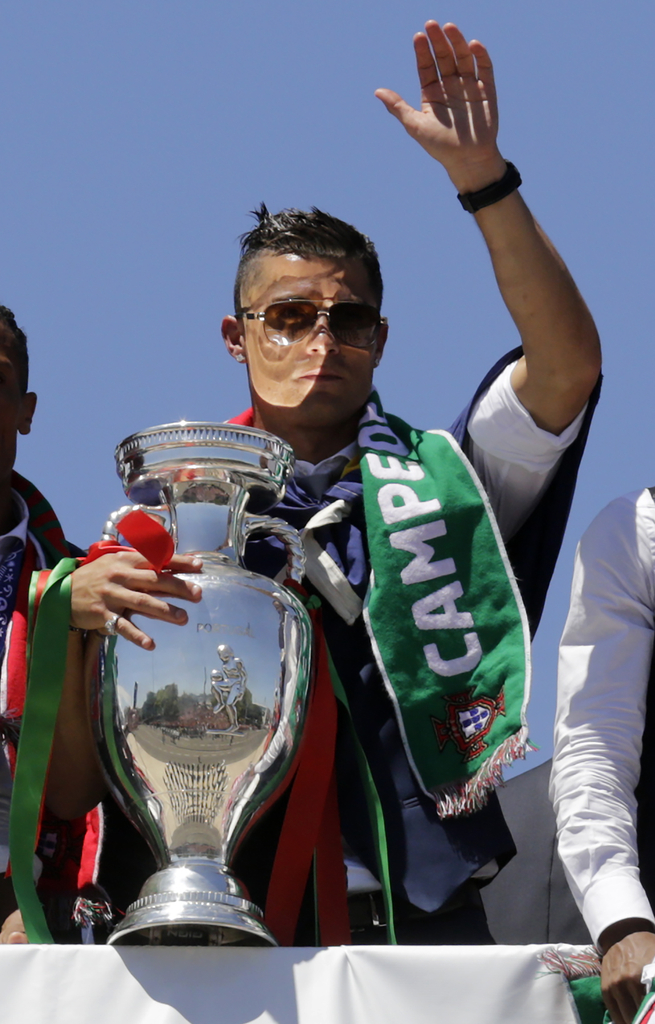 2016年7月11日，葡萄牙里斯本，2016年欧洲杯冠军葡萄牙队回到国内，全体队员和教练乘坐大巴游行并受到葡萄牙总统的接见，全城民众欢欣舞动狂欢庆祝。图为C罗向球迷挥手