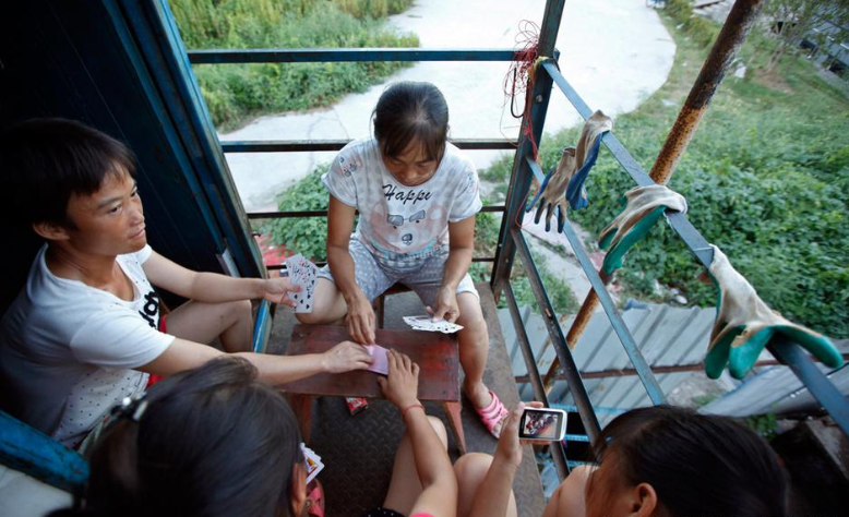 6月10日，工地停工，贵州来的几个女民工正聚在一起打牌。长期与亲人、爱人分居，情感世界空虚的她们，棋牌、电视是唯一的消遣娱乐方式。 摄影来源/关爱农民工在行动