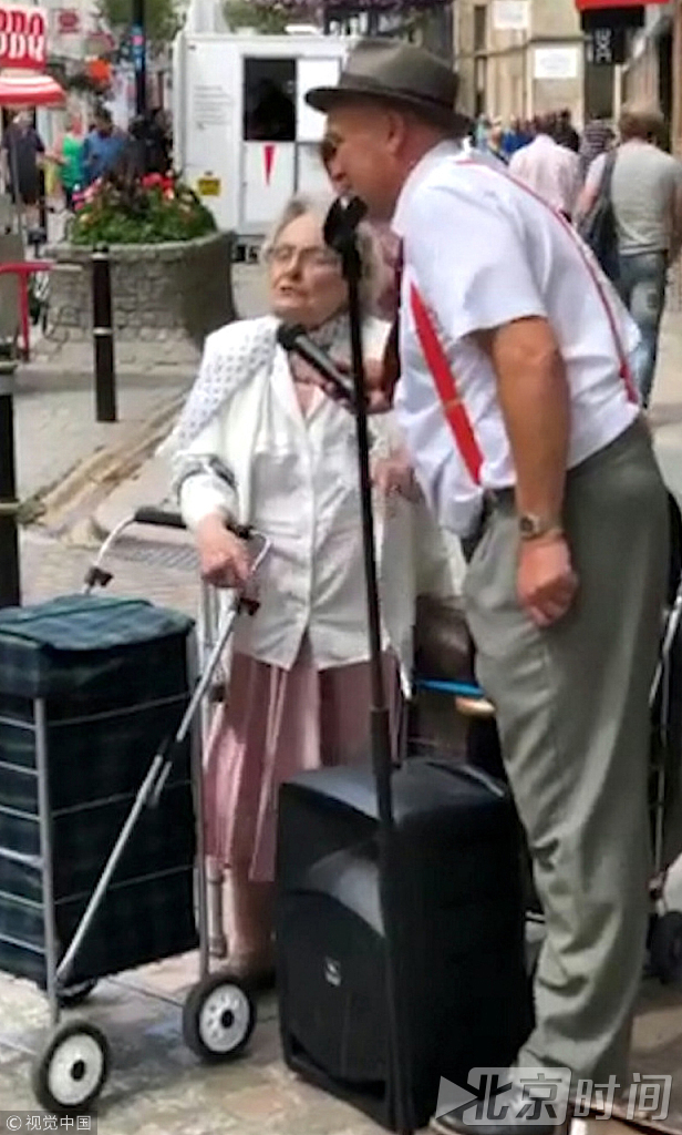 这段影像素材记录下来了一位88岁的退休老人Enid Bellamy在繁忙的特鲁罗市中心驻足与街头艺人Andy Marshall二重唱的暖心一幕。