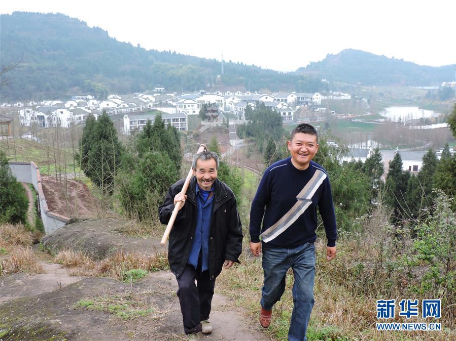 3月12日，四川省达州市渠县万寿乡灵感村“第一书记”、退伍军人廖阳（右一）和村民裴云俄行走在6组的山路上。身后是廖阳协助建成的远近有名的农旅基地徽派山水建筑“碧瑶山庄”。新华社发（邓良奎 摄）