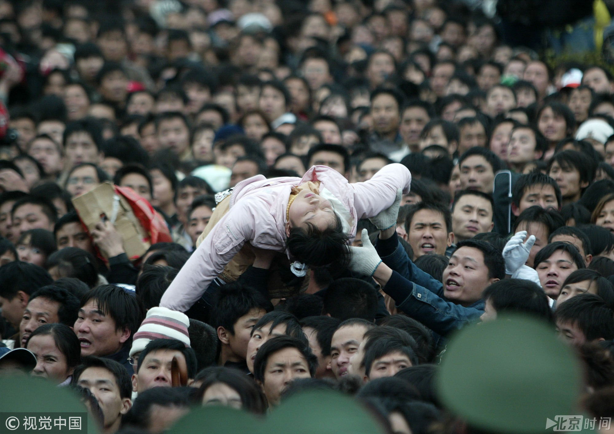 2008年1月31日，广州，部分列车恢复运行，大批乘客聚集在火车站广场外准备进站。一乘客晕倒在人群中，乘客把其抬高救出。图/视觉中国