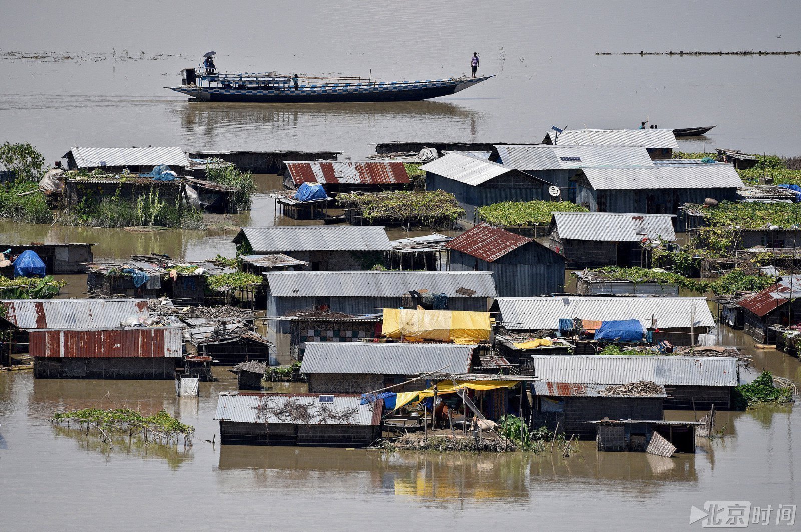 当地时间2017年7月14日,印度阿萨姆邦,民众乘船离开被淹的村庄