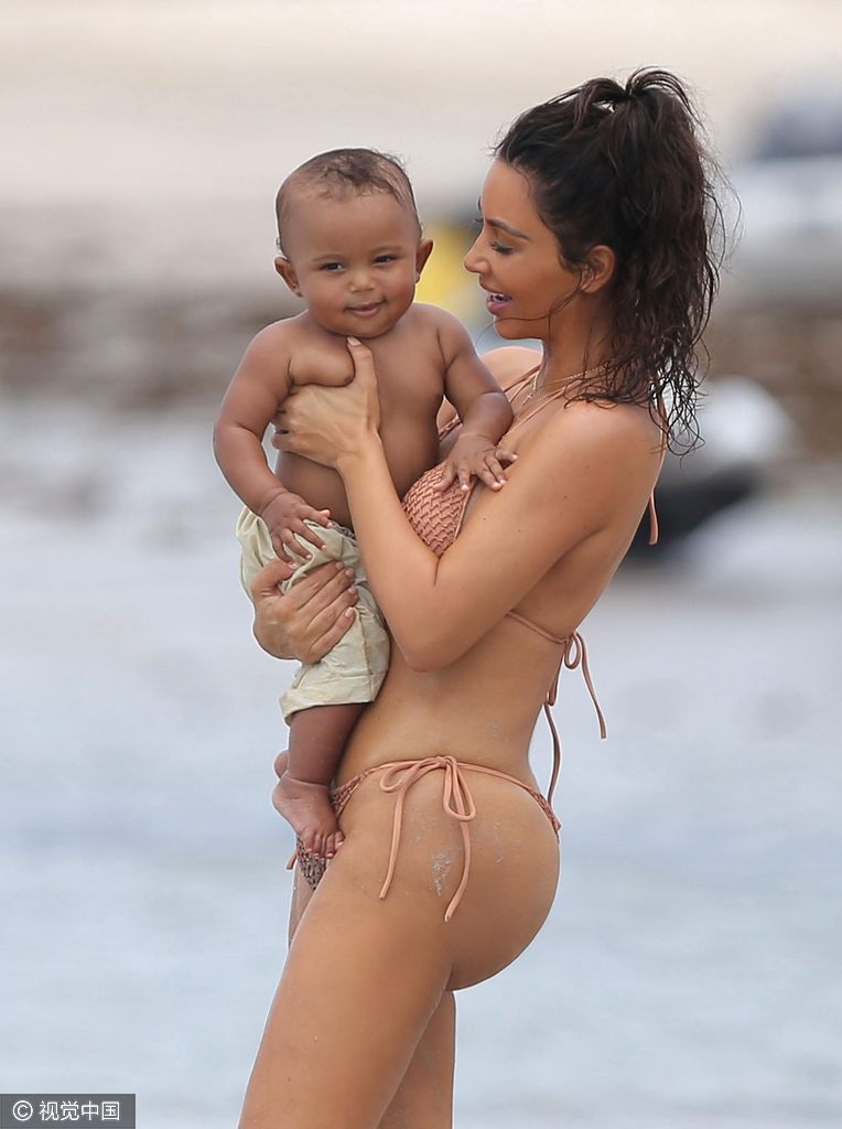 当地时间8月18日，金·卡戴珊（Kim Kardashian）带女儿小西北和儿子沙滩玩耍，卡戴珊身穿裸色系带比基尼，女儿与妈妈同款可爱十足，在沙滩上卡戴珊全程呵护幼子母爱爆棚，然而抢镜的还是翘臀。图为卡戴珊与幼子耳语。