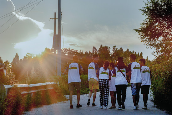 7月29日,在四川"快乐学校"活动中,做完家访的志愿者们并肩走在小路