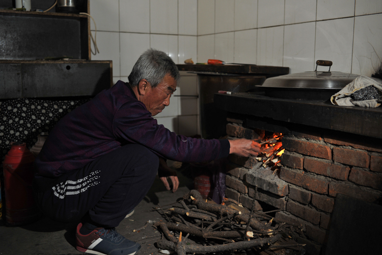 2月4日,李玉宝在灶头烧火,蒸包子.