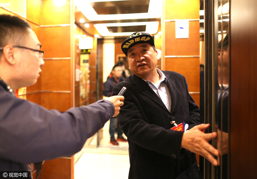北京会议中心政协委员驻地，记者在电梯口拦住姜昆进行采访，姜昆一边回答问题一边始终用手挡着电梯，防止自动门关闭。
