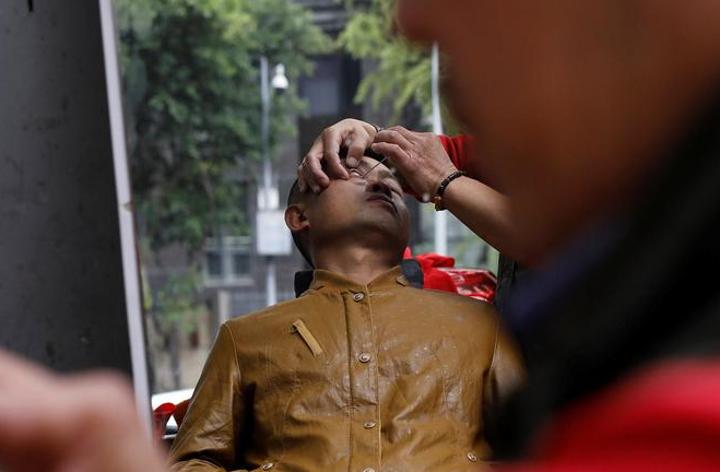 2017年11月18日，四川成都，62岁的街头理发师熊高武为顾客展示刀锋洗眼。熊高武自17岁起就在街头理发。人称“熊三师”的他有三个独门绝技：刀锋洗眼、跳三刀、舒筋。其中最令人称绝的就是刀锋洗眼也就是用锋利的刀片“扫”眼皮，据说只要体验过一次，就不会忘记。