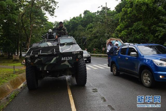 菲律宾南部棉兰老岛公路边，居民乘车撤离马拉维市，菲政府军士兵坐在装甲车上休息，准备向马拉维进发。