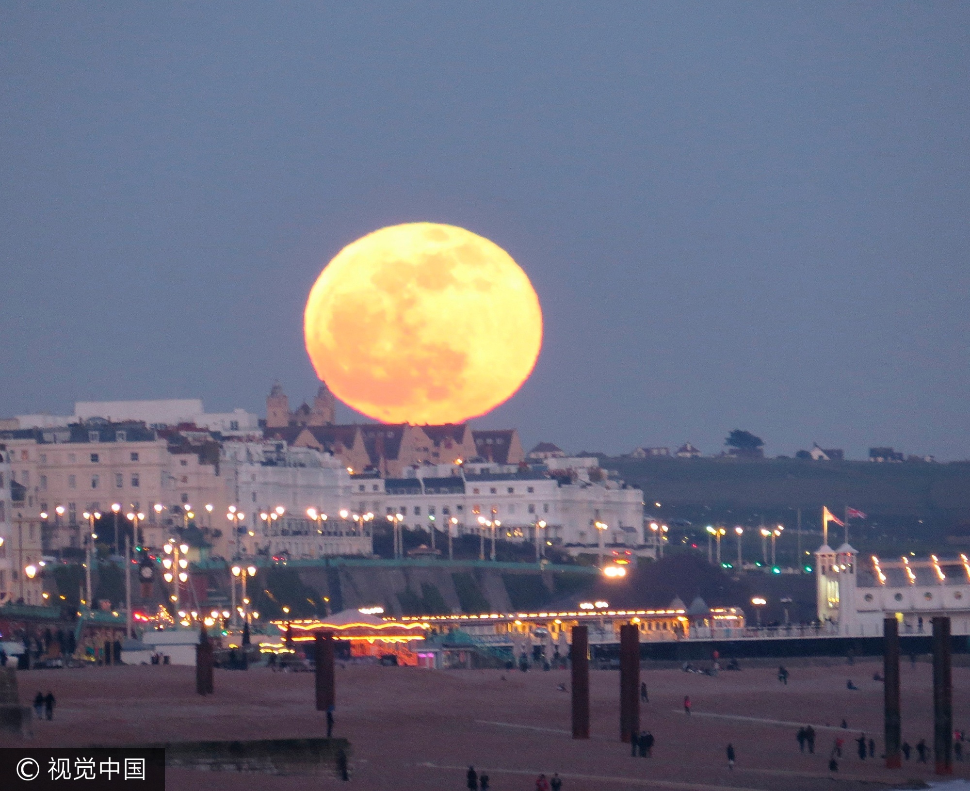 2015年4月9日消息(具体拍摄时间不详),英国东萨塞克斯布赖顿,一轮壮观的橙色月亮出现的布赖顿海边建筑上方,震惊了观者。 Louise Goodall和家人在海滩上散步的时候,看到了这一景观,迅速拿起相机拍摄下来。