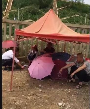 角落撑起了一个临时帐篷,几把彩色的雨伞围出相对私密干净的空间。那里静静地躺着一对母子,在大雨中,他们再也没能回家。