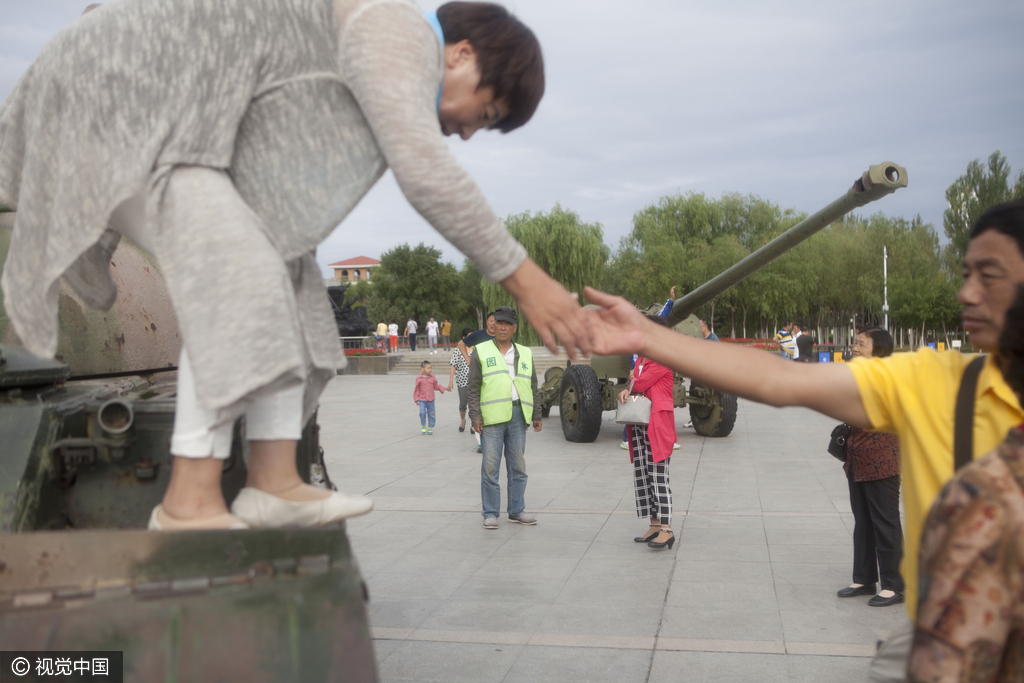 2016年08月10日，黑龙江省齐齐哈尔市，广场现坦克飞机，市民组团攀爬合影。