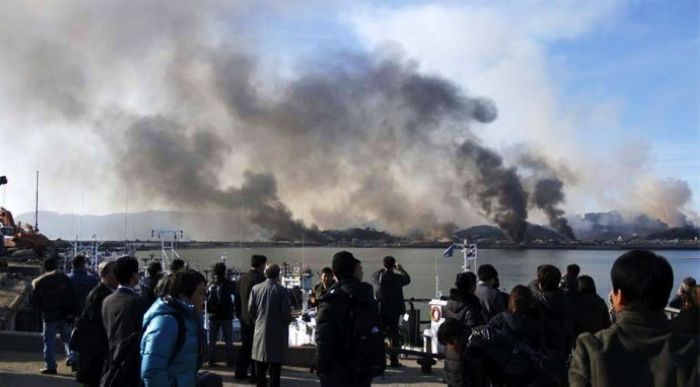 当地时间下午约2点34分，朝鲜人民军在毫无预警的情况下突然向韩国延坪岛炮兵阵地射击。据称朝方使用的是122毫米口径火箭炮，共发射约200发火箭弹，延坪岛上的韩国军事设施随即在炮击中起火。朝鲜人民军开火6分钟后，韩国方面用K-9自行火炮向朝鲜海岸炮部队基地还击。图为民众在远处观察炮战。