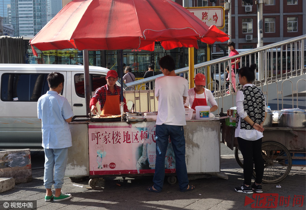 2015年7月29日，北京朝阳路红庙路口，马路边人行便道上的夫妻档早餐车。
