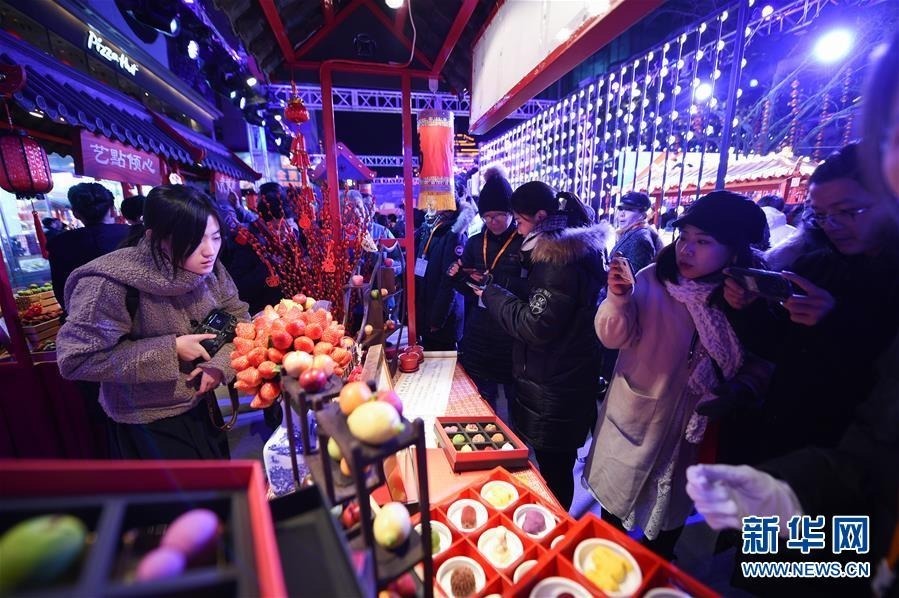 12月20日，游客在开街活动上观看民族饭店展台展出的点心。新华社记者 鞠焕宗 摄