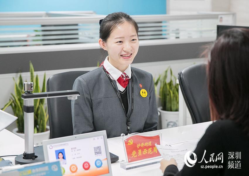 图为沙井街道政务服务中心党员佩戴党徽为市民提供微笑政务服务.