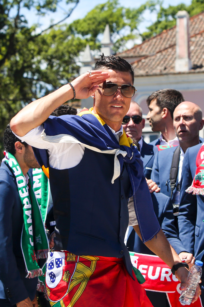 2016年7月11日，葡萄牙里斯本，2016年欧洲杯冠军葡萄牙队回到国内，全体队员和教练乘坐大巴游行并受到葡萄牙总统的接见，全城民众欢欣舞动狂欢庆祝。图为C罗向大家致意