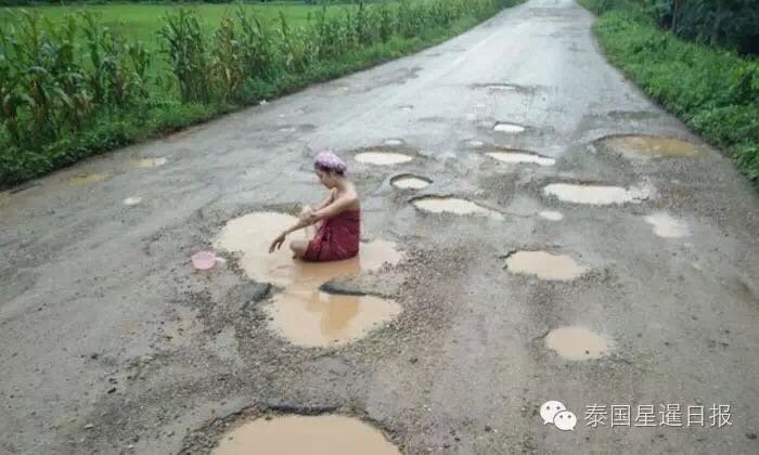 为了引起路管部门重视 女子在路坑积水中洗澡