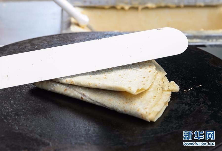 在德国首都柏林,一名可丽饼摊位的工作人员折叠可丽饼。