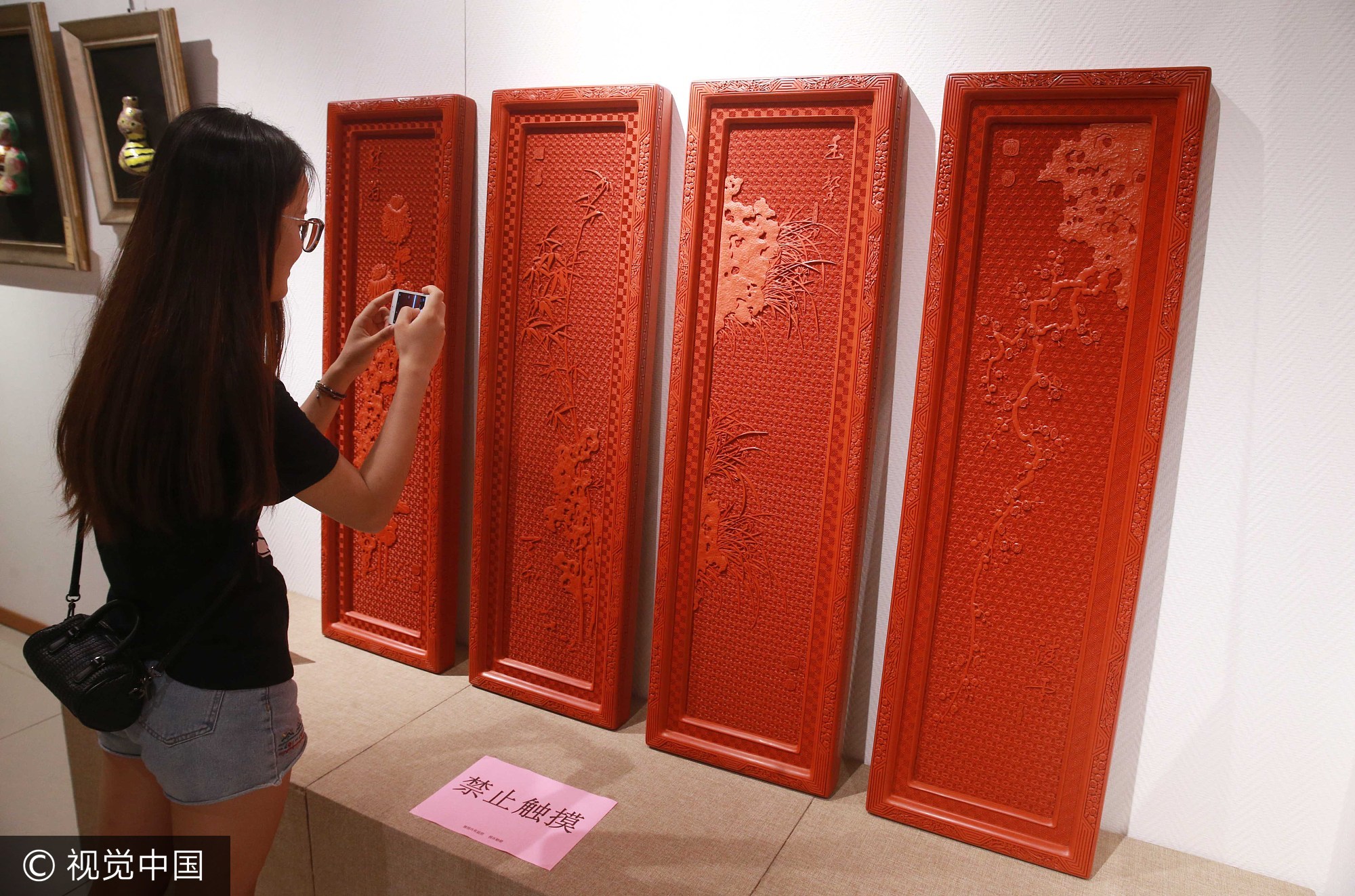 2017年9月3日，观众在北京工艺美术创新设计大赛作品展上用手机拍摄雕漆工艺作品《剔红梅兰竹菊四扇挂屏》。