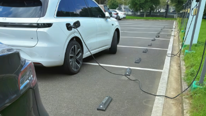 新能源车充电将线拉出停车场,车辆停在机动车道充电 新能源车充电将线拉出停车场,车辆停在机动车道充电