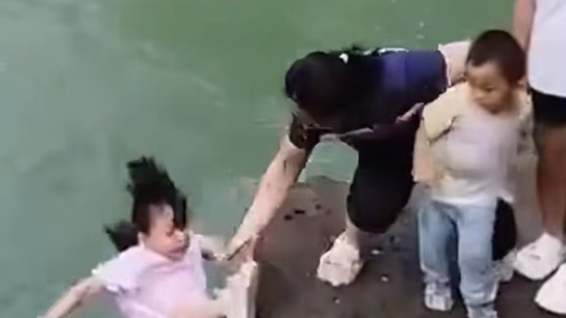 女孩河边拍照被碰到水里 幸好旁边大哥及时拉住_北京时间